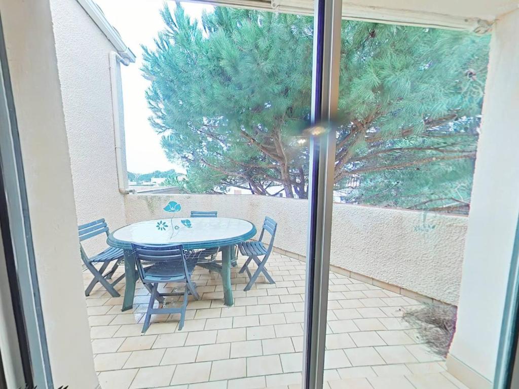 d'une terrasse avec une table, des chaises et un arbre. dans l'établissement Proche Mer - Appartement avec terrasse sans vis a vis, à Saint Pierre La Mer