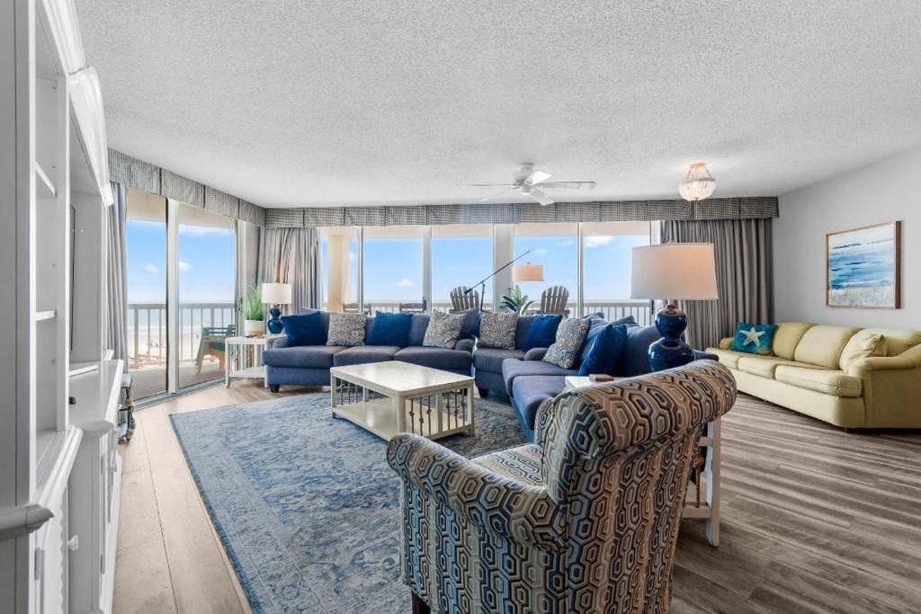 a living room with blue furniture and a large window at Beachfront Oasis at Litchfield By the Sea: 3 Bdrm in Pawleys Island