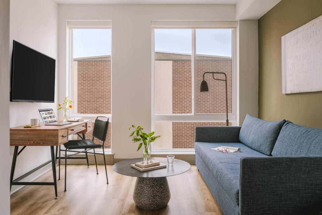 a living room with a blue couch and a desk at Sonder The Sloan in Philadelphia