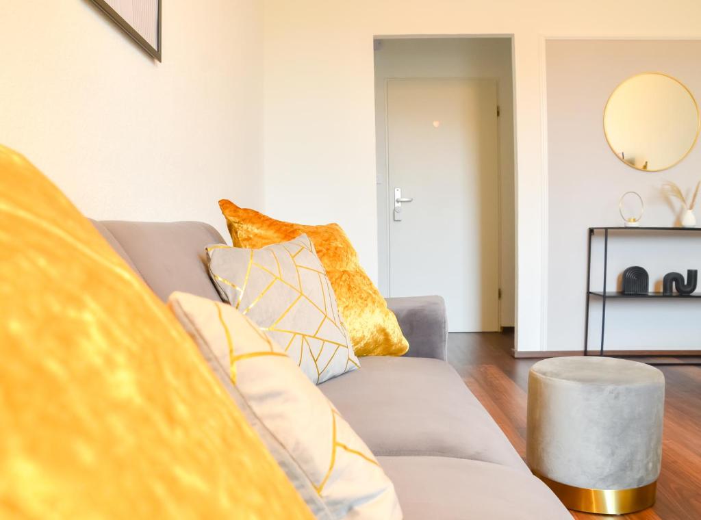 a living room with a gray couch with yellow pillows at MILPAU Buer 3 - Modernes und zentrales Premium-Apartment mit Queensize-Bett, Netflix, Nespresso und Smart-TV in Gelsenkirchen