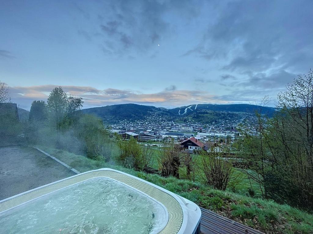 een hot tub met uitzicht op de stad bij Chalet de standing 14 personnes in Gérardmer