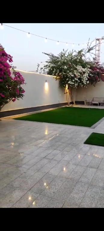a courtyard with a white wall and green grass at شاليه تريك in Buraydah