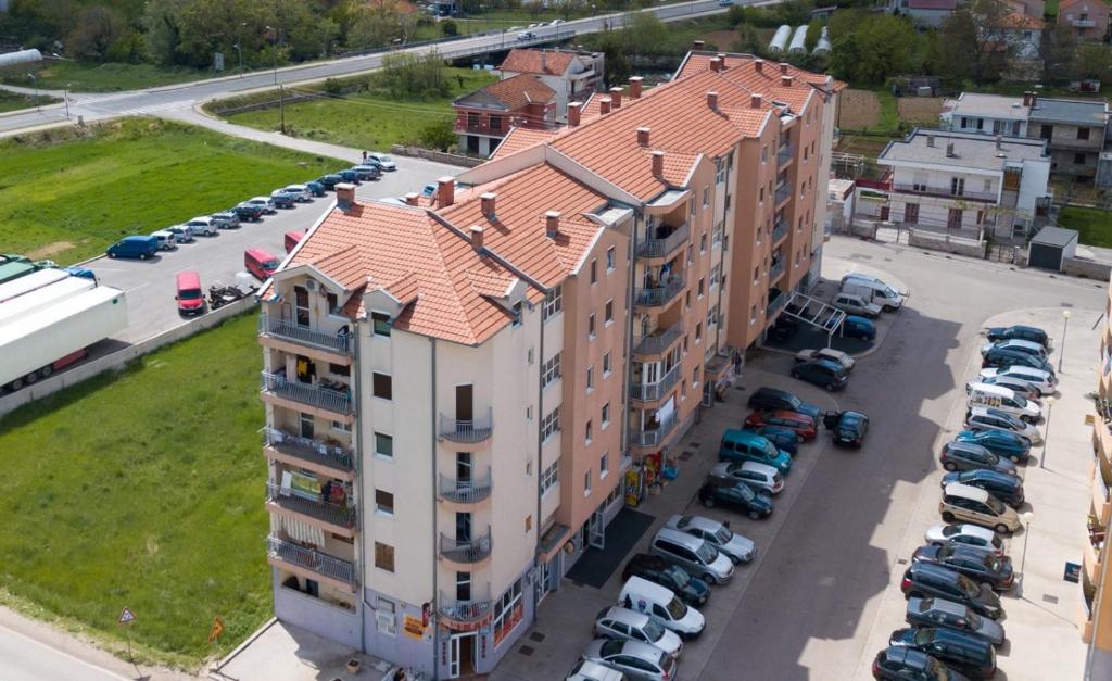 an apartment building with a red roof in a parking lot at Apartments TEA in Trebinje