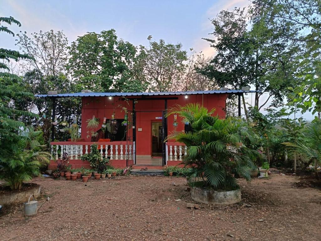 una casa roja con un porche en el bosque en Kittur Guest House, en Dharwad
