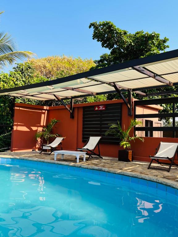 una piscina con due sedie a sdraio e un ombrellone nel patio di Chris Espace a Toliara