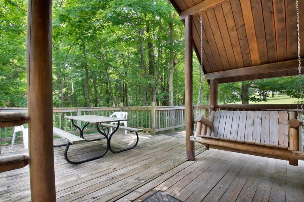 a porch with a bench and a table on it at Rustic Cabin in Lake Monroe in Bloomington