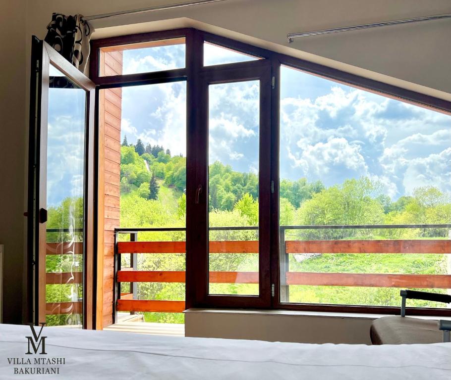 Schlafzimmer mit einem großen Fenster mit Blick auf die Bäume in der Unterkunft Villa Mtashi in Bakuriani