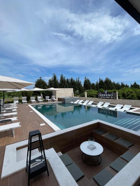 une grande piscine avec des chaises longues et une table dans l'établissement Sereno Village, à Ulcinj