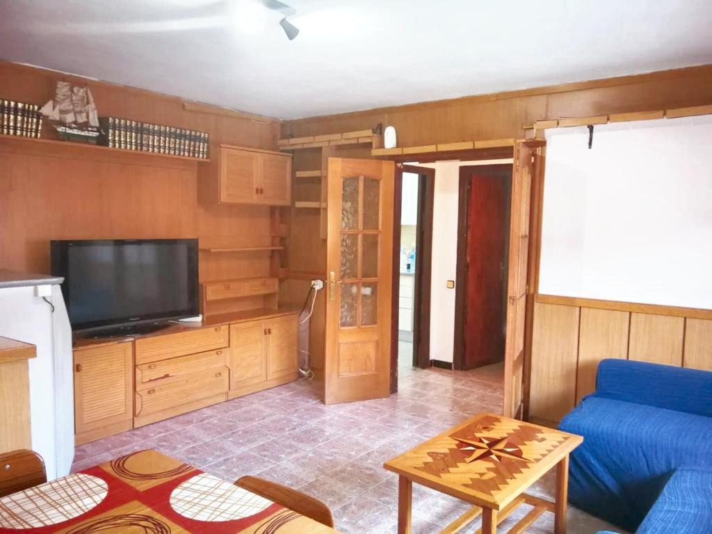 un salon avec un canapé bleu et une télévision dans l'établissement 3 bedrooms house with city view balcony and wifi at Esparreguera, à Esparraguera