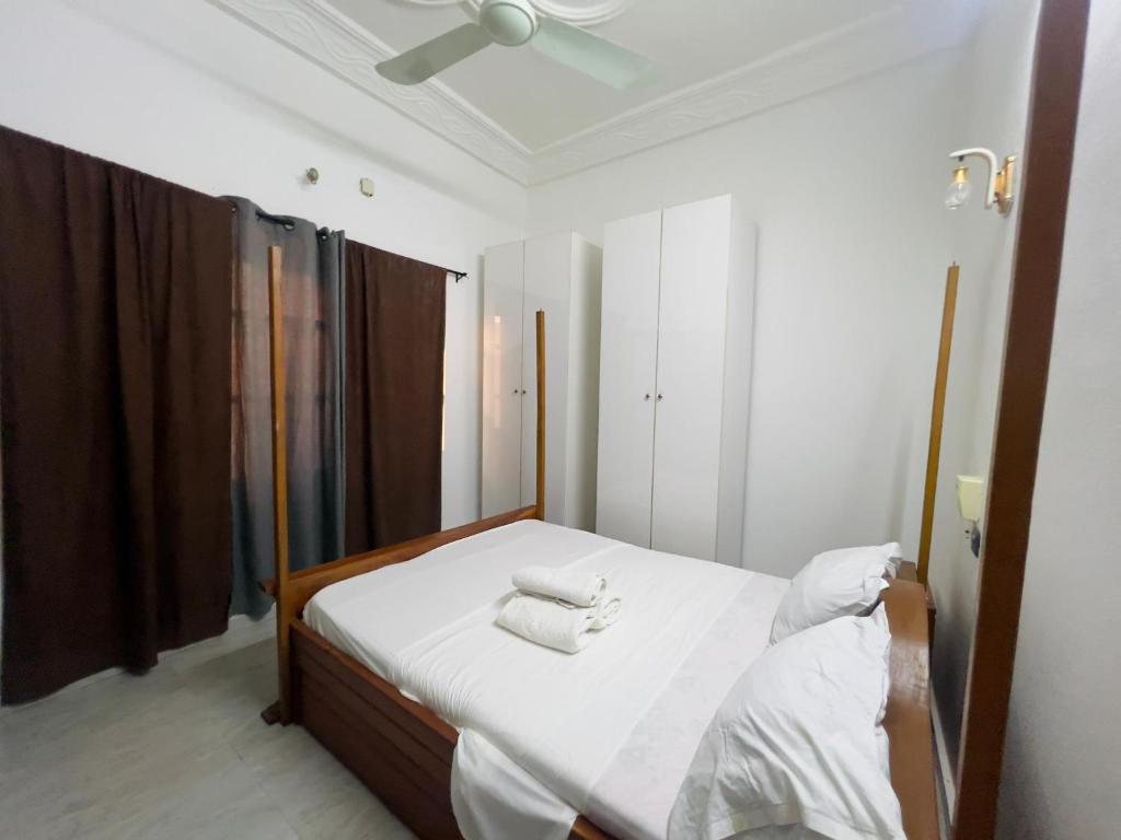 - une chambre avec un lit doté de draps blancs et de serviettes dans l'établissement Luxe Club, à Cotonou