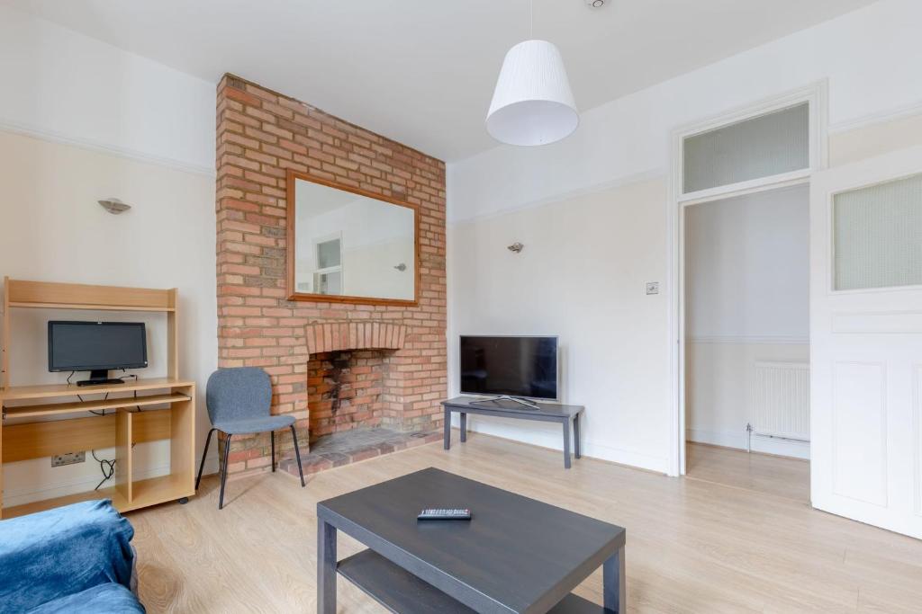 een woonkamer met een bakstenen open haard en een tv bij Roomy 3BD by Hampstead Heath! in Londen
