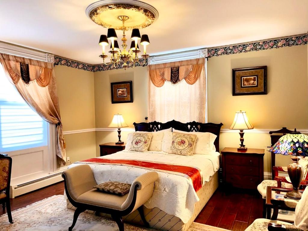 a bedroom with a bed and a chair and a chandelier at Grape Suite-heart of oldtown in Niagara on the Lake