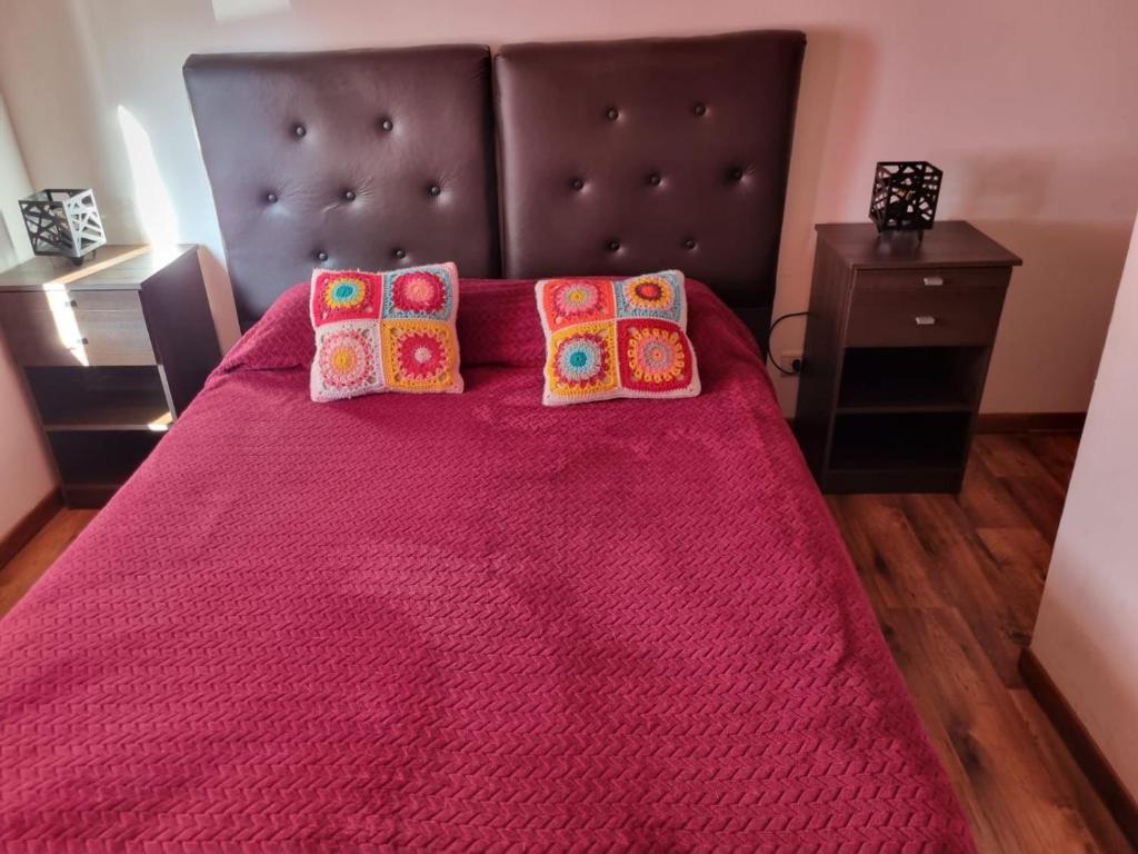 um quarto com uma cama grande e um cobertor rosa em Cabaña Ceferino Ushuaia em Ushuaia