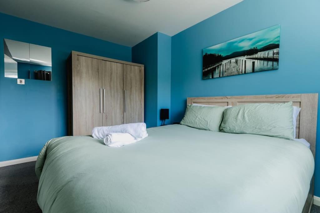 a bedroom with a large bed with blue walls at Hullidays 3 bed House Hull West Calvert in Hull