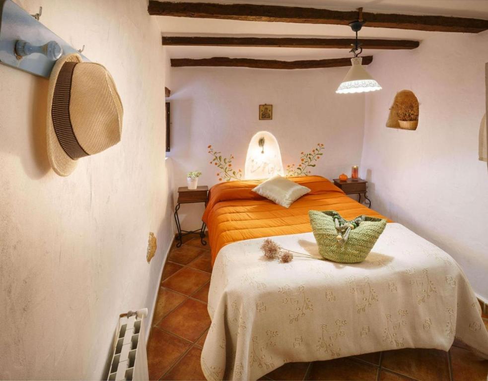 Laroya的住宿－Casa Rural La Curiosa，一间卧室配有橙色的床和桌子