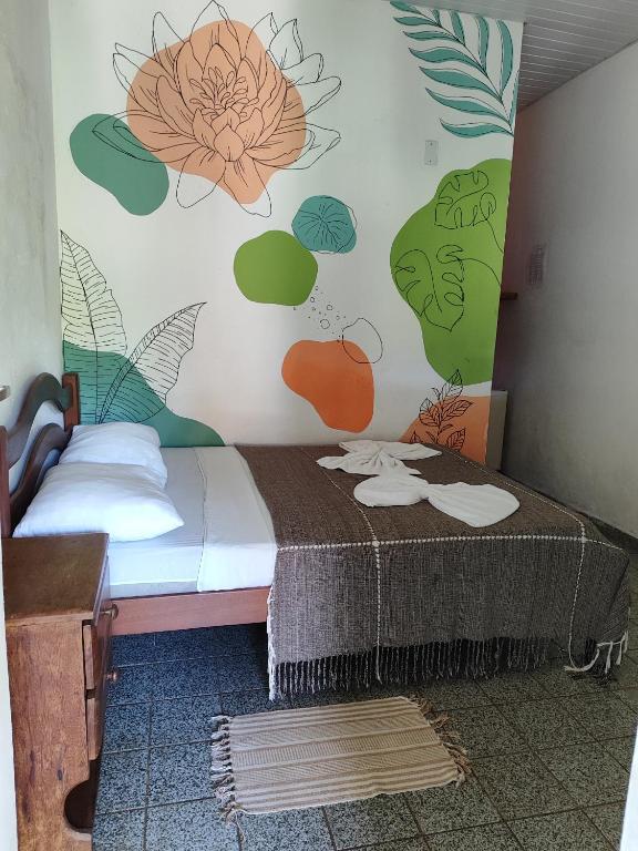 1 dormitorio con 1 cama con un mural de flores en la pared en Pousada Carambola en Pipa