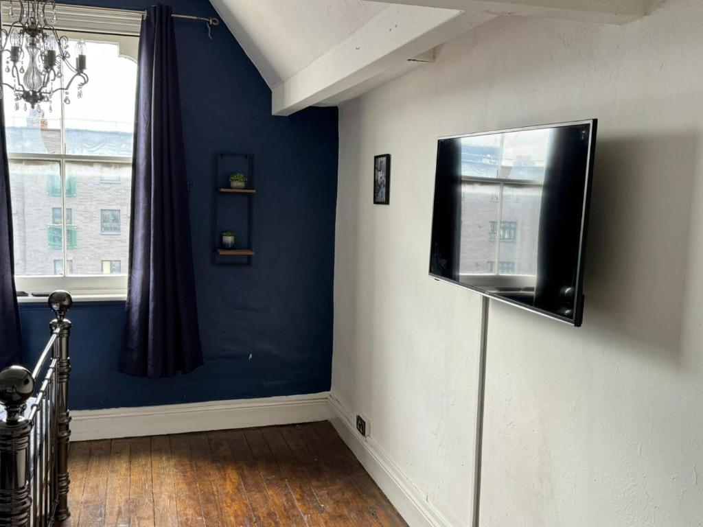 a room with a blue wall with a flat screen tv at Premium Dighbeth in Birmingham
