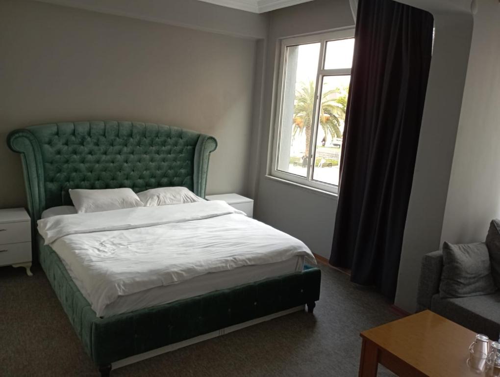 um quarto com uma cama com uma cabeceira verde e uma janela em Samsun Otel Vidinli em Samsun