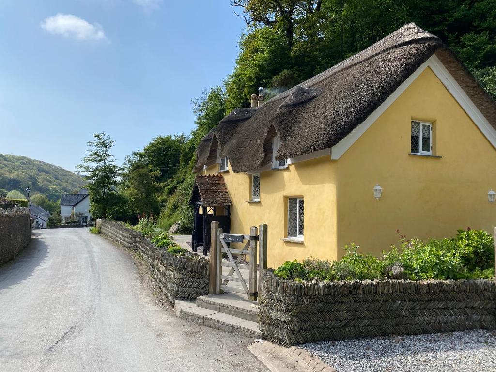 a yellow house with a thatched roof on a street at Old Maids Cottage in Ilfracombe