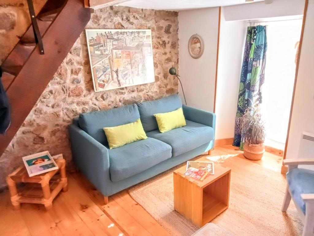 L'Atelier de Pierre Gîte Atypique في Saint-Cyr: غرفة معيشة مع أريكة زرقاء ووسائد صفراء