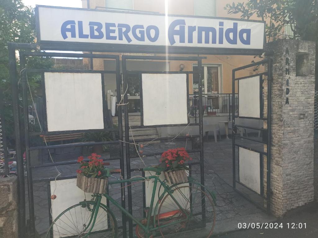 un vélo garé devant un immeuble avec un panneau dans l'établissement Hotel Armida, à Laigueglia