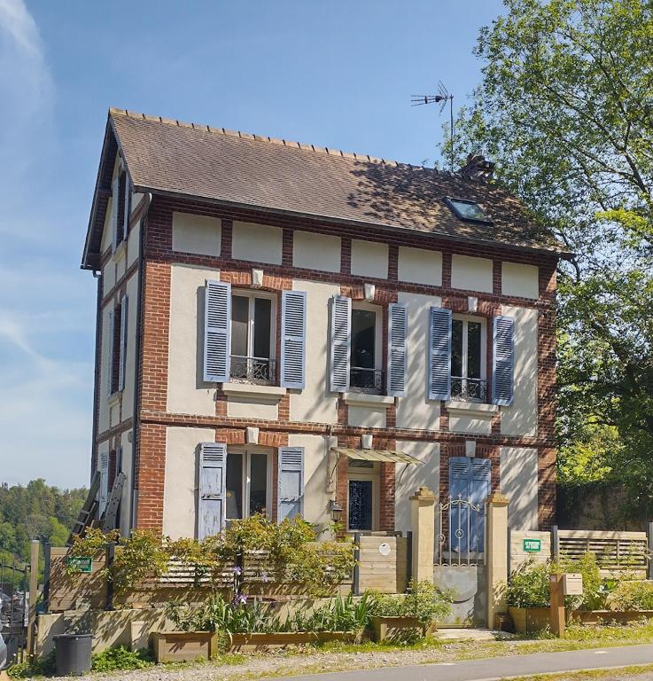 une vieille maison en briques avec des volets bleus dans une rue dans l'établissement Hill Cottage, à Équemauville