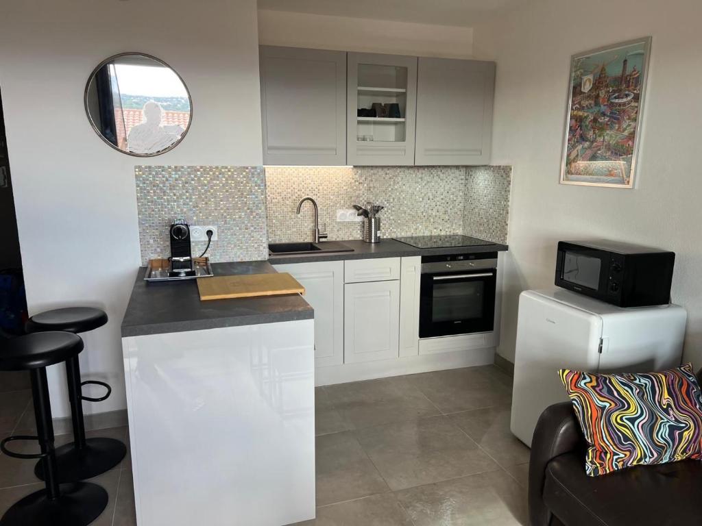 une cuisine avec des armoires blanches, un évier et un micro-ondes dans l'établissement Appartement vue mer et piscine, à Saint-Raphaël