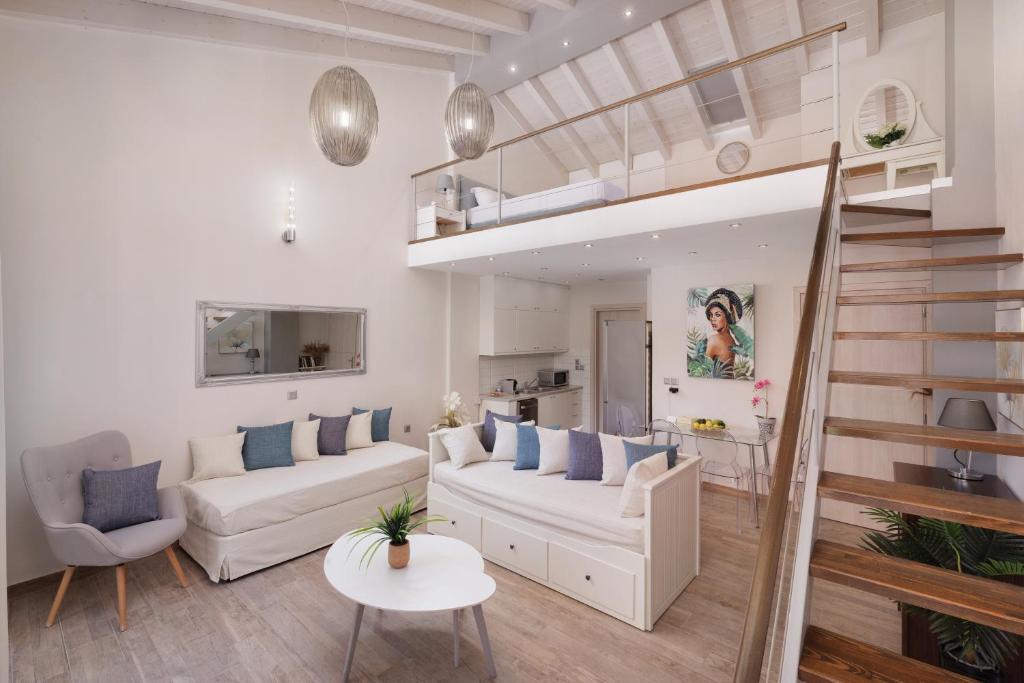 una sala de estar con muebles blancos y una escalera. en Corfu Town Luxury Studios -A en Corfú