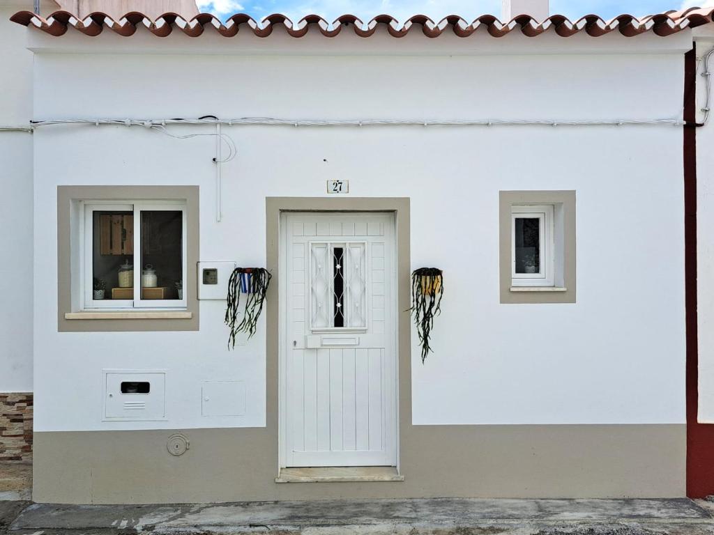 a white building with a door and two windows at Refúgio do Alqueva in São Marcos do Campo