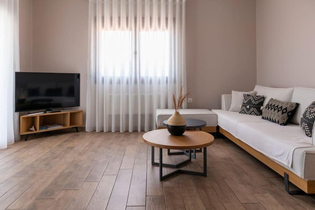 a living room with a white couch and a tv at Koukounaraki Apartment 1 in Skiathos