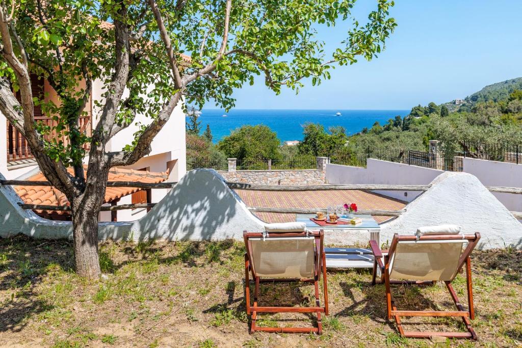 einen Tisch und zwei Stühle unter einem Baum in der Unterkunft Naiades Nest in Emerald Skopelos in Skopelos