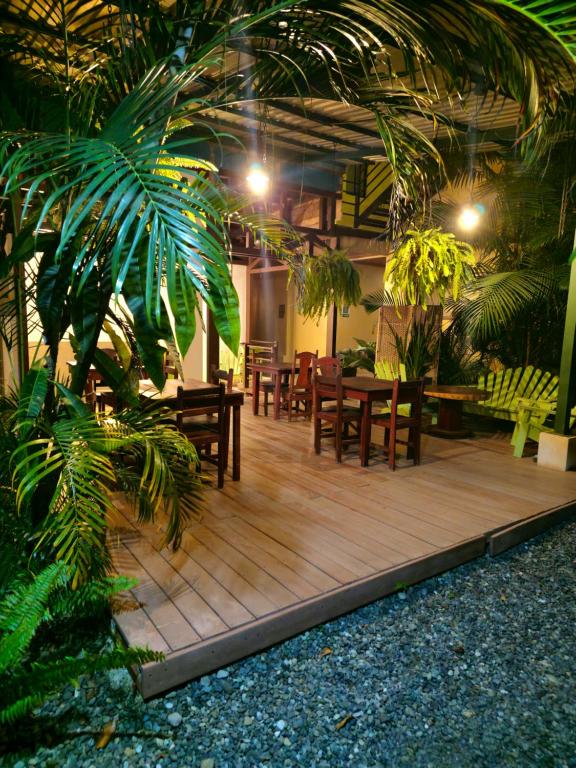 eine Terrasse mit Tischen, Stühlen und einer Palme in der Unterkunft Caribbean Sea Towers Hotel in Puerto Viejo