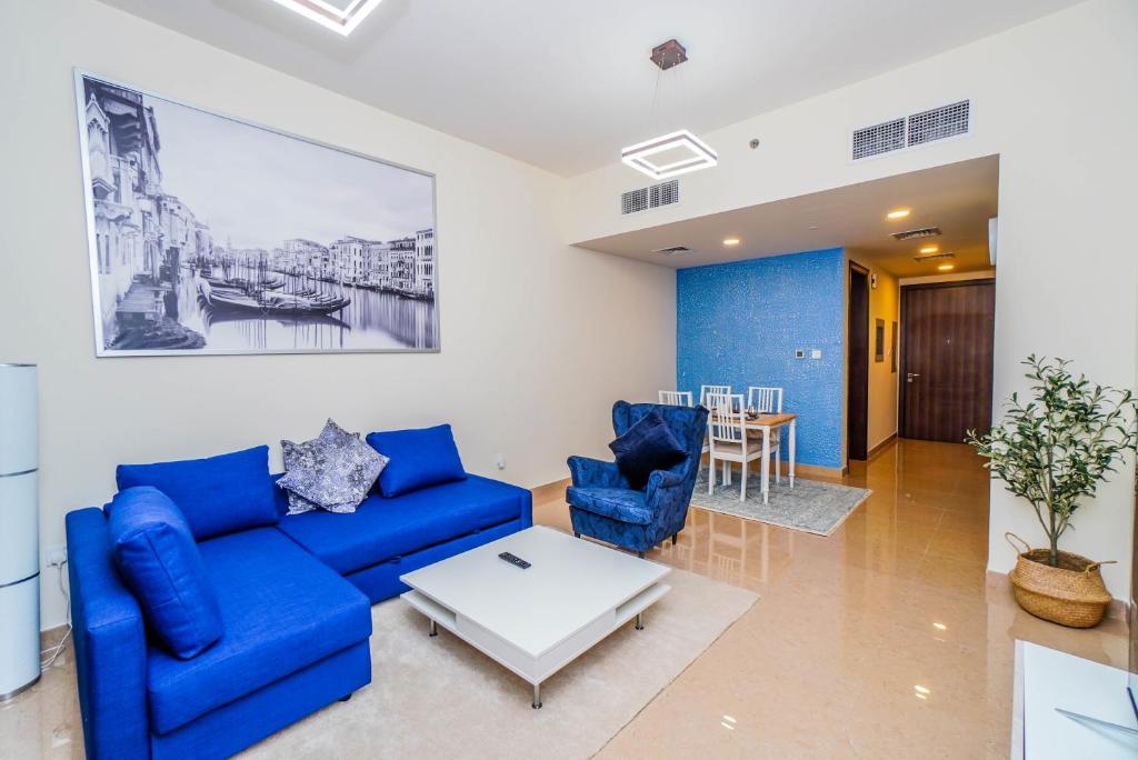 sala de estar con sofá azul y mesa en 1 BR Apt, Miracle Garden with RoofTop Pool, King Bed, Gym,100mbps en Dubái