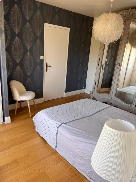 une chambre avec un grand lit et une chaise dans l'établissement Appartement de charme vue sur Loire, à Nantes
