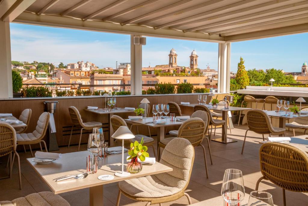 restauracja ze stołami i krzesłami oraz widokiem na miasto w obiekcie The First Arte - Preferred Hotels & Resorts w Rzymie