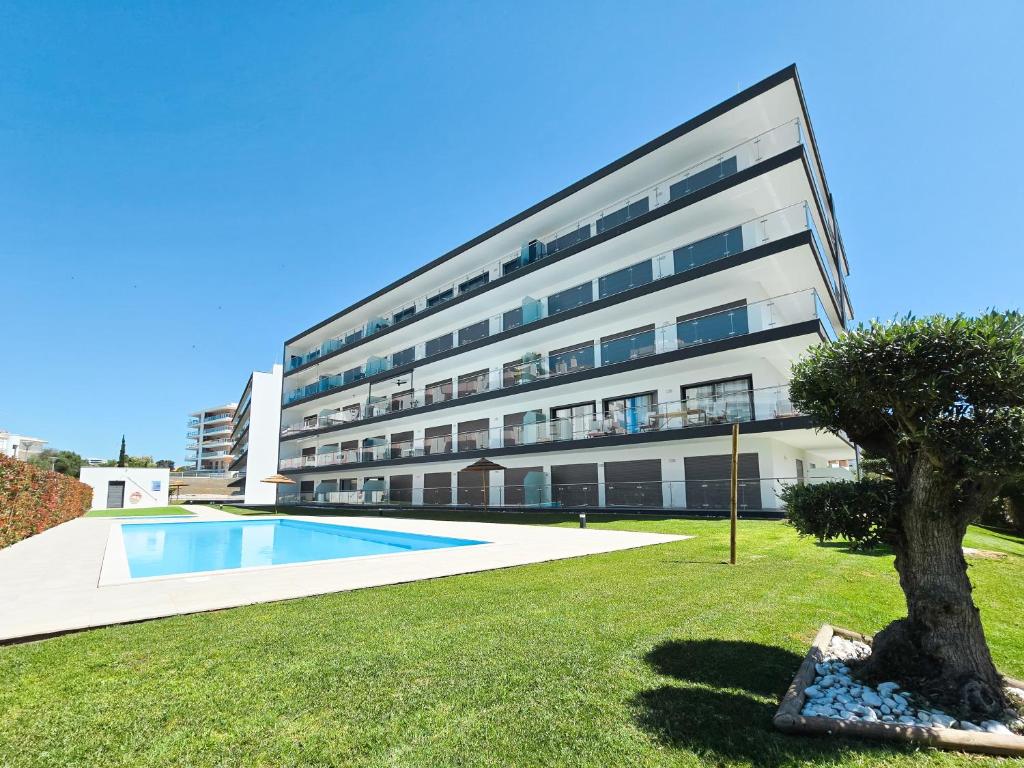 un edificio de apartamentos con piscina y un árbol en Apartment Praia Rocha Residence Honey Glow, en Portimão