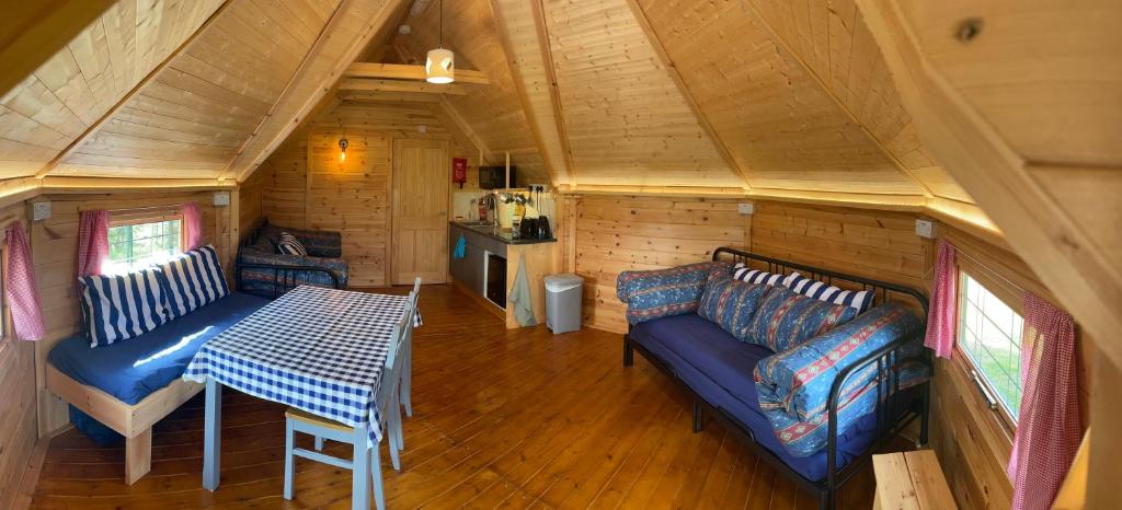 - une chambre avec un canapé et une table dans une petite maison dans l'établissement Holly Tree Glamping Cabins, à Wigglesworth