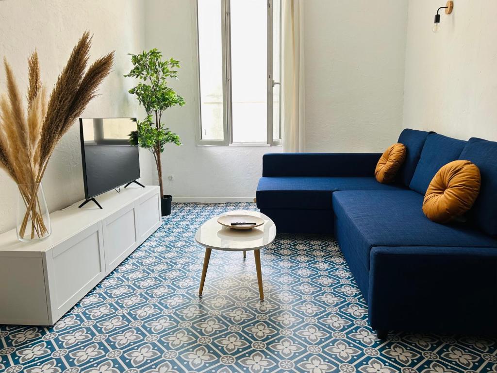 un salon avec un canapé bleu et une télévision dans l'établissement L'Aixalté - T2, Vieille Ville, à Aix-en-Provence