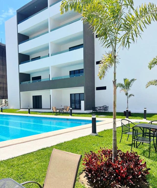 a building with a swimming pool and a palm tree at Marina Cerritos Coral del Mar - 4 Albercas de Lujo - 1 Min Playas in Mazatlán