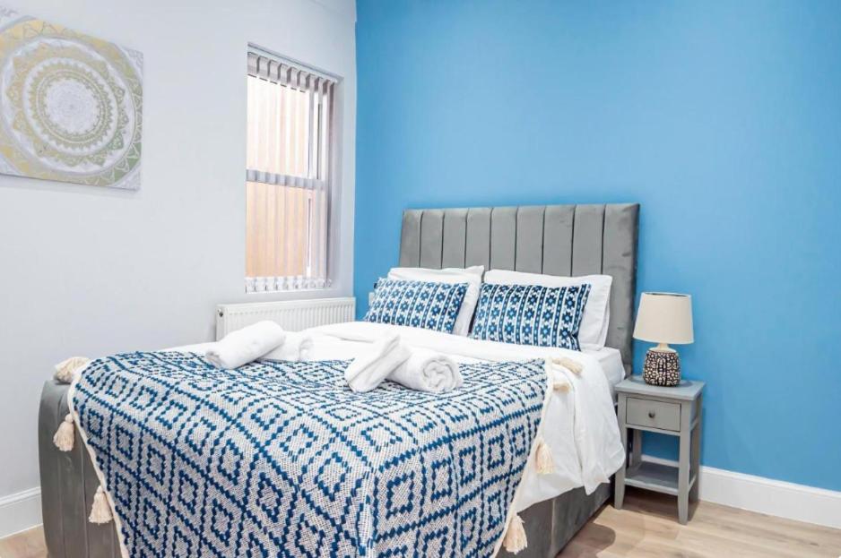een blauwe slaapkamer met een bed met handdoeken erop bij High-end Stylish Apartments - **CENTRALLY LOCATED** in Reading