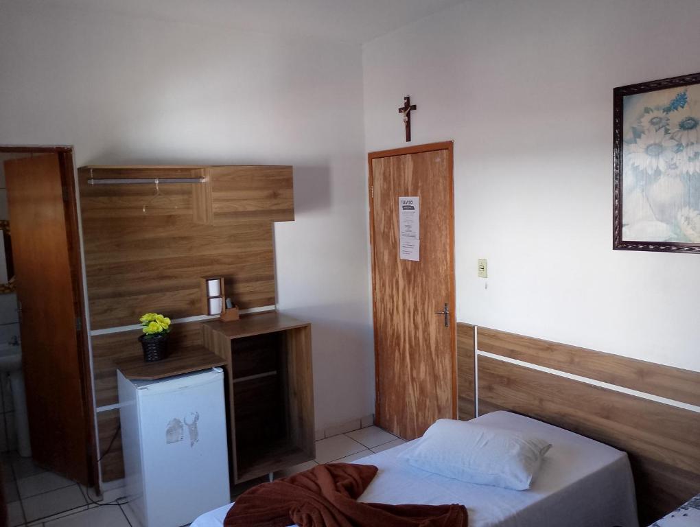 Habitación con cama y cruz en la pared en Hotel Portal dos anjos en Aparecida