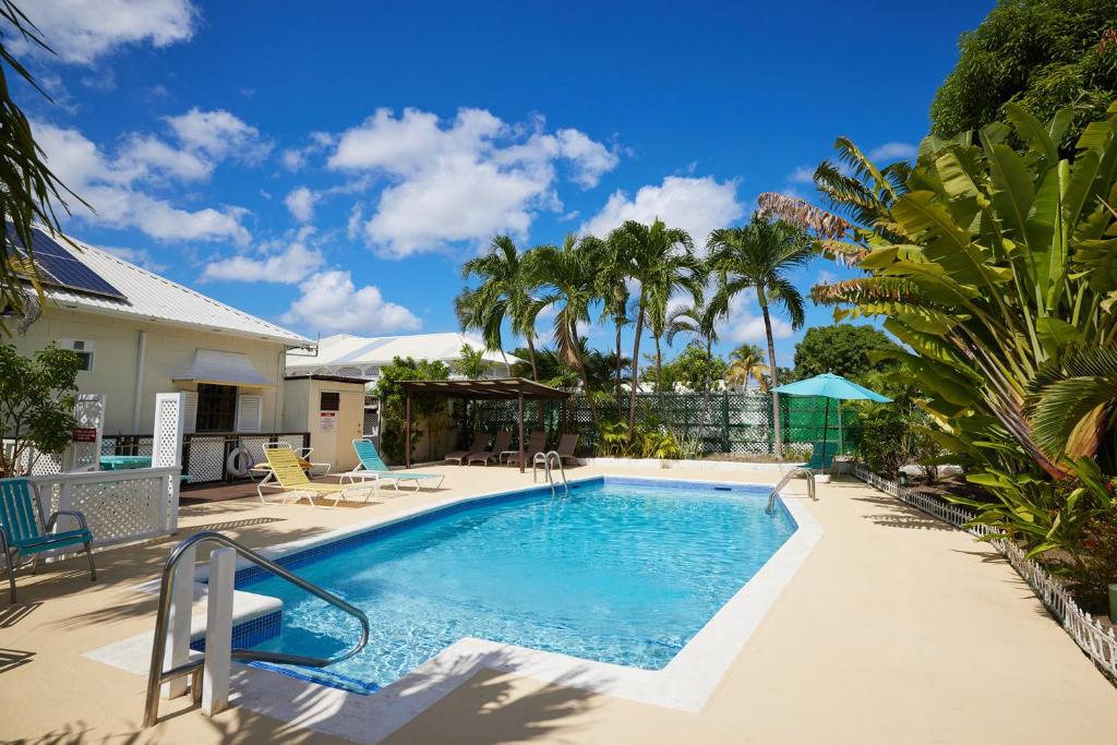 uma piscina com palmeiras e uma casa em Southern Surf Beach Apartments em Bridgetown