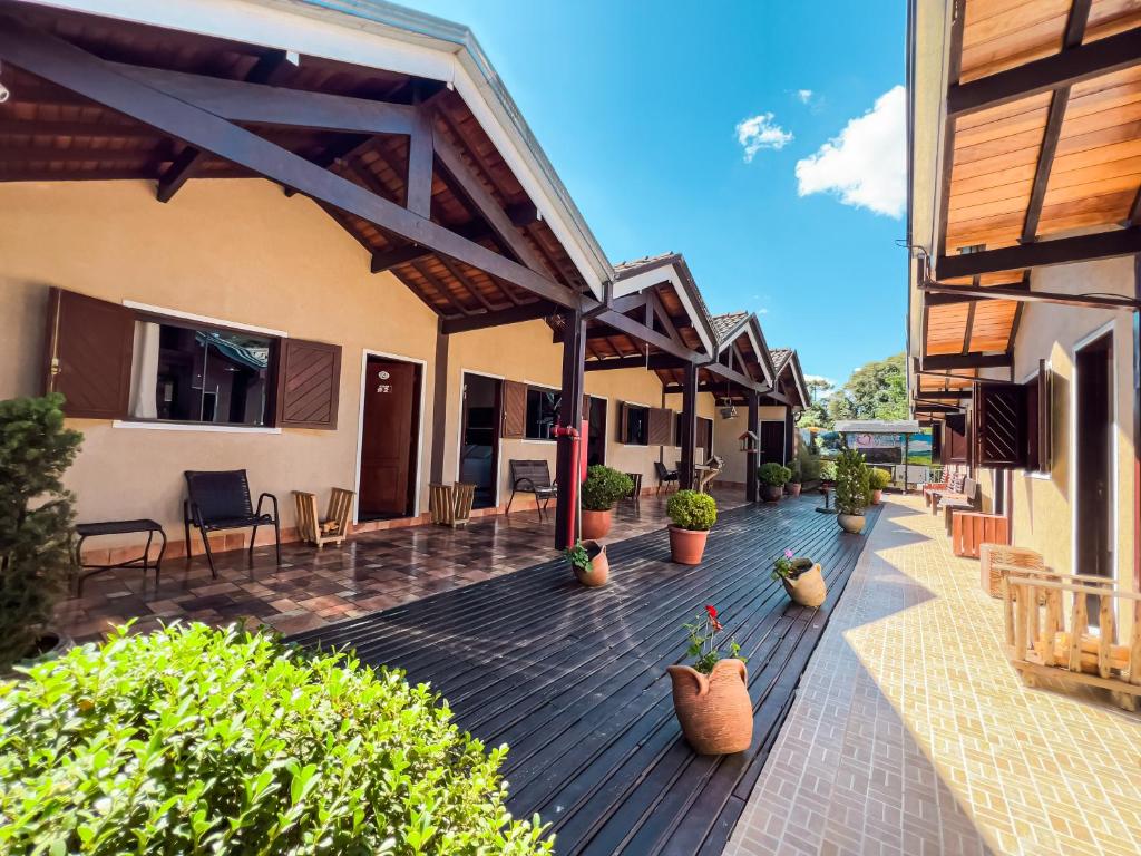 an outdoor deck with chairs and potted plants at Chalés Galinha Da Roça in Monte Verde