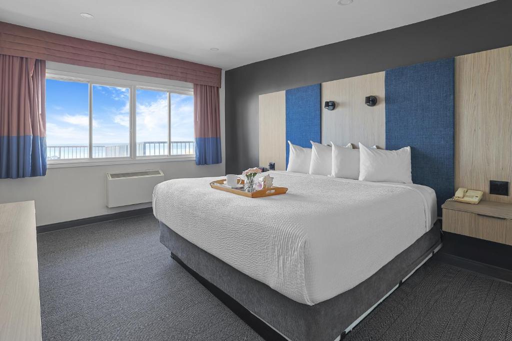 a hotel room with a large bed and a large window at Ramada by Wyndham Jordan/Beacon Harbourside Resort in Jordan