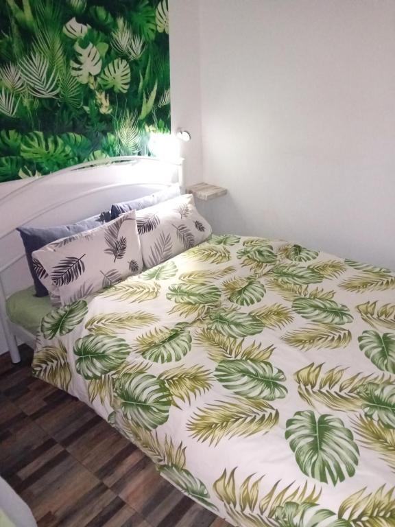 een bed met een groene en witte deken en kussens bij Panda apartment in Thessaloniki