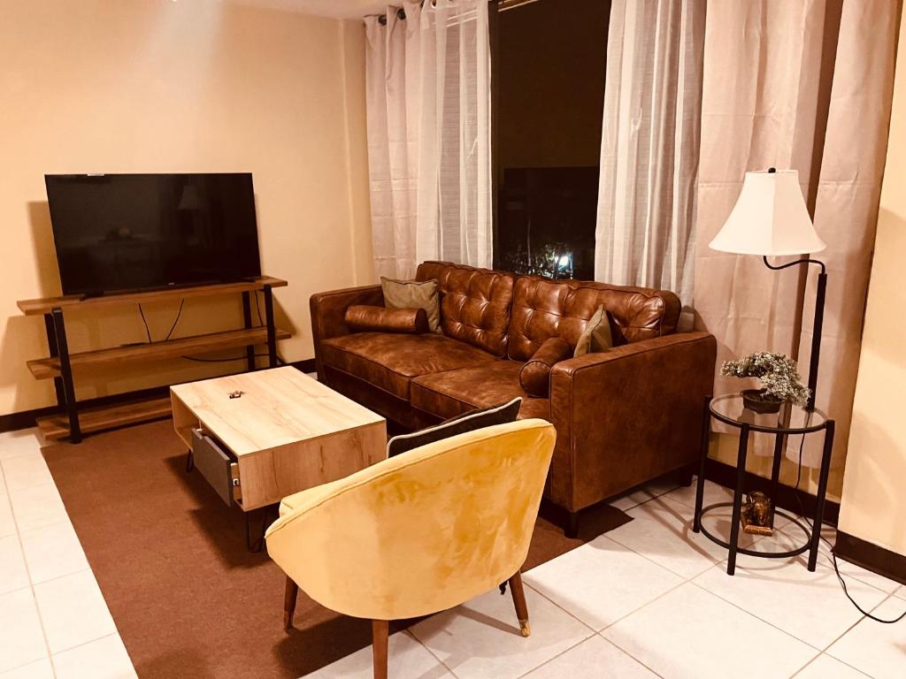 uma sala de estar com um sofá de couro castanho e uma televisão em Apartamentos Carmela # 3 em Siguatepeque