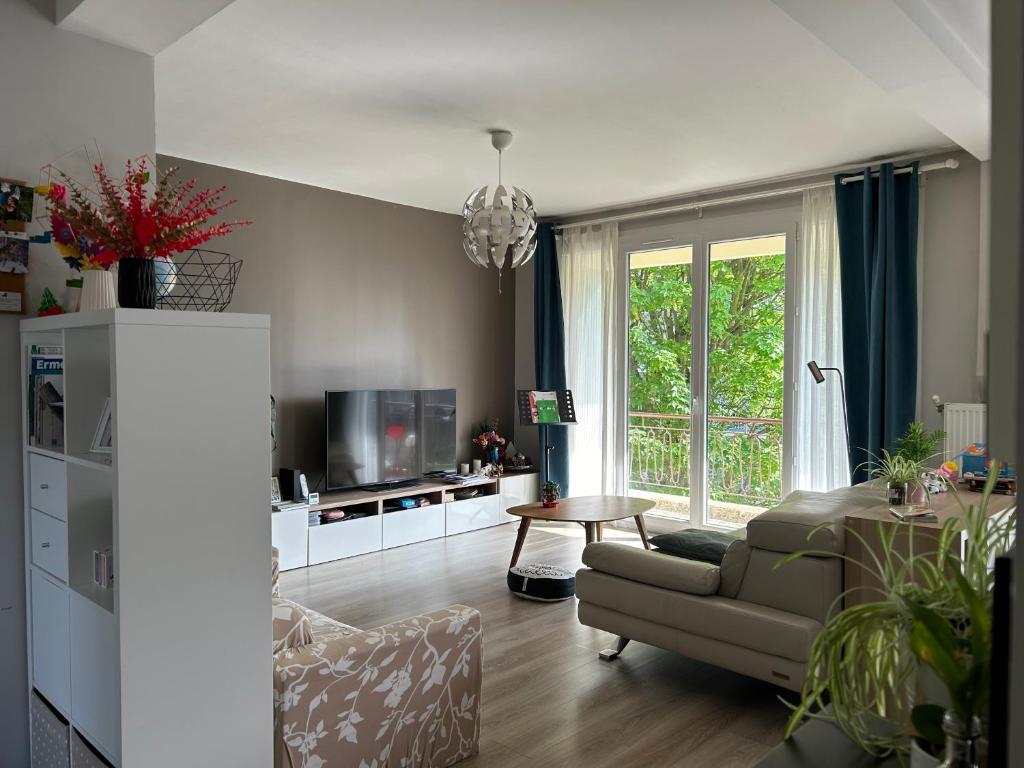 un salon avec un canapé et une télévision dans l'établissement Summer - appartement 20 mins to Paris - JO 2024, à Ermont