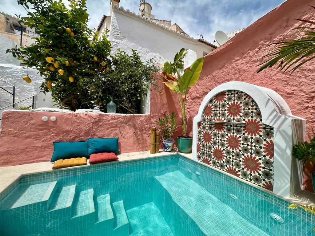 a swimming pool in front of a pink wall with a swimming pool at Casa Limonero in Sedella