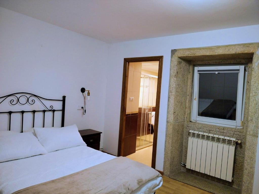 1 dormitorio con cama blanca y ventana en Casa Cal da Rosins, en Muxía