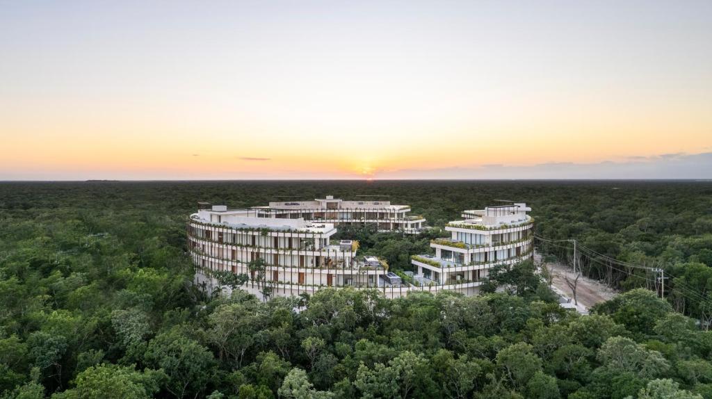 une vue aérienne d'un immeuble d'appartements avec le coucher de soleil en arrière-plan dans l'établissement Mistiq Temple I, à Tulum